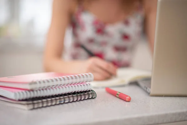 Une pile de cahiers en spirale et fille étudiante à l'ordinateur portable Image En Vente