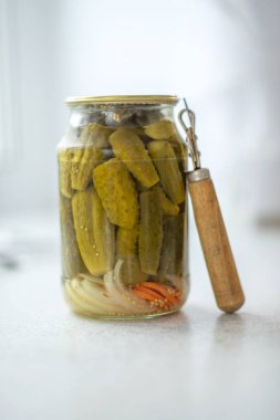 Açacağı ile beyaz bir arka plan üzerinde cam kavanozda salatalık turşusu