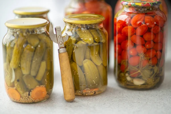 Pickled cucumbers and tomatoes in glass jar on a white background with opener — Stock Photo, Image