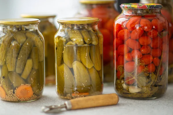Pickled cucumbers and tomatoes in glass jar on a white background with opener — Stock Photo, Image