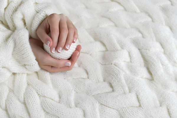 Mujeres hermosas manos con manicura francesa en el fondo de un suéter blanco cálido — Foto de Stock