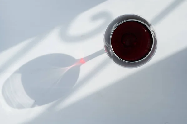 Ein Glas Rotwein auf weißem Hintergrund mit einem Schattenspiel — Stockfoto