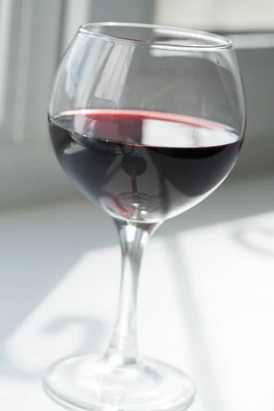 Una copa de vino tinto sobre un fondo blanco con un juego de sombras — Foto de Stock