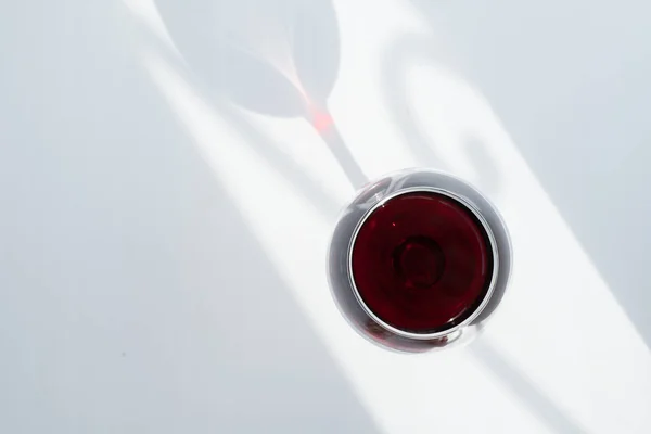 Ein Glas Rotwein auf weißem Hintergrund mit einem Schattenspiel — Stockfoto