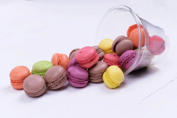 Colorful mini macarons a scattering of packaging on white background, sweet — Stock Photo, Image