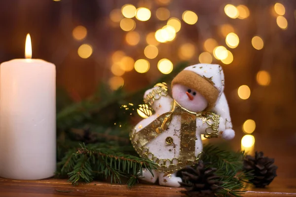 Karácsonyfa ágak, egy hóember és egy gyertyát. Bokeh a háttérben. Karácsonyi üdvözlőlap — Stock Fotó