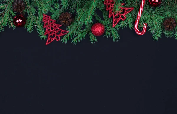 Rami di abete rosso, palle di Natale, caramelle su sfondo nero, preparazione per il nuovo anno. vista dall'alto, copia spase — Foto Stock