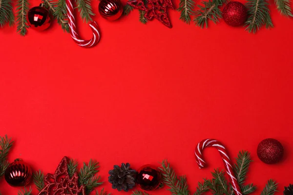 Spar takken met kerstballen en snoep op een rode achtergrond, bovenaanzicht, kopieer spaas, mock up — Stockfoto