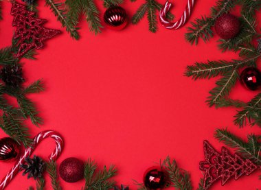 Spruce dalları, Noel baloları, kırmızı arka planda şekerler, yeni yıla hazırlık. Üst görünüm, bölmeyi kopyala