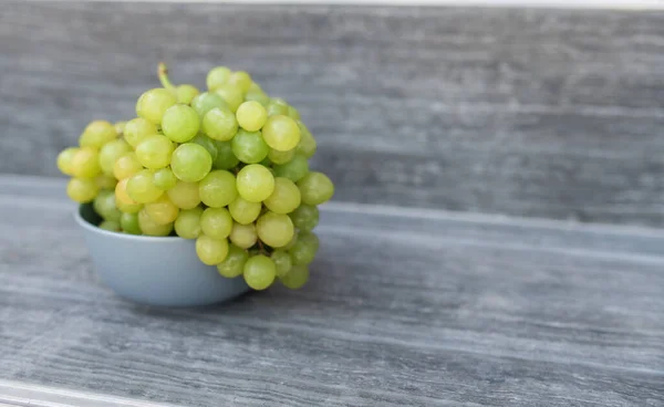 A bunch of ripe green grapes in a gray plat on a gray background. — Stock Image A bunch of ripe green grapes in a gray plat on a gray background. Stock Picture