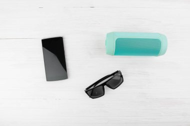 Akıllı telefon sonraki kablosuz taşınabilir hoparlör ve siyah güneş gözlüğü yaz tatili kavramı üzerinde beyaz tahta arka plan en iyi açılı görünüş için siyah.