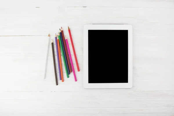 大きな黒い空画面スマートな白い木製の背景上部角にカラフルな鉛筆の横にタブレット デバイス — ストック写真
