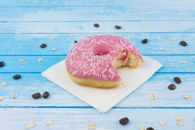 Lezzetli tatlı çörek kağıt üzerine çizilmiş mavi beyaz yüksek karşıtlık tahıl yulaf yemek ve kahve çekirdekleri ahşap arka plan üzerinde üzerinde Closeup ısırıldı