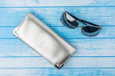 Mavi ve beyaz tahta arka plan en iyi açı üzerinde yanında moda gözlüklü zarif Modenr kadın yansıtıcı malzeme çantası