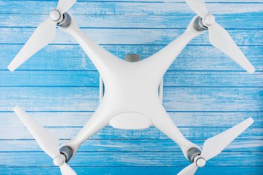 Modern High Tech büyük beyaz Drone ile mavi ve beyaz boyalı ahşap arka plan Quadcopter kavramı en iyi açı üzerinde bağlı pervaneleri