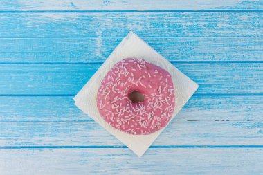 Lezzetli tatlı pembe çörek üzerinde kağıt üzerine çizilmiş mavi beyaz yüksek karşıtlık ahşap arka plan en iyi açı