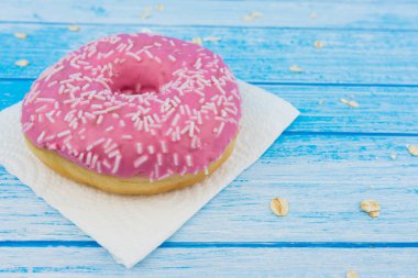 Lezzetli tatlı pembe çörek üzerinde kağıt üzerine çizilmiş mavi beyaz yüksek kontrast bütün tahıl yulaf yemek üstünde o ile ahşap arka plan portre