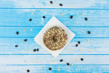 Lezzetli tatlı çörek üzerinde kağıt üzerine çizilmiş mavi beyaz yüksek kontrast tahıl yulaf yemek ve kahve çekirdekleri ile ahşap arka plan üzerinde en iyi açı