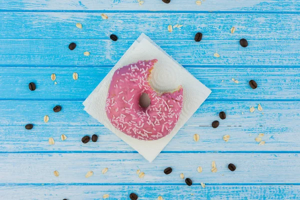 Lezzetli tatlı çörek kağıt üzerine çizilmiş mavi beyaz yüksek karşıtlık tahıl yulaf yemek ve kahve çekirdekleri ahşap arka plan üzerinde üzerinde üstten görünüm ısırıldı