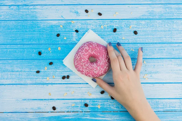 Mulher Mão Segurando Saboroso Doce Rosa Donut Papel Fundo Madeira — Fotografia de Stock
