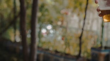 Holding ve yavaş şeffaf plastik bir kap Light bira ile sallayarak adam el 