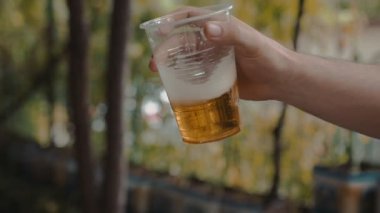 Holding ve yavaş şeffaf plastik bir kap Light bira ile sallayarak adam el 