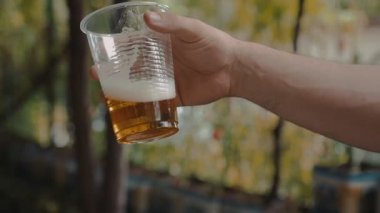 Holding ve yavaş şeffaf plastik bir kap Light bira ile sallayarak adam el 