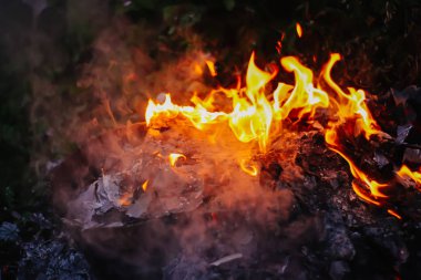 Açık havada yeşil yaz çimlerinde kağıt yanıyor..