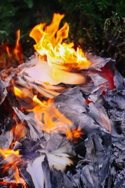 Açık havada yeşil yaz çimlerinde kağıt yanıyor..