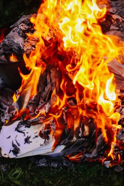 Açık havada yeşil yaz çimlerinde kağıt yanıyor..