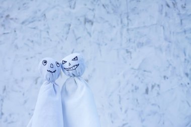 Cadılar Bayramı için dekorasyon. Işıklı arka planda iki hayalet figürü. Parti için el yapımı dekor.