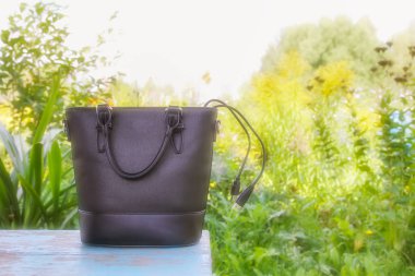 Dışarıdaki ahşap bankta kablo olan siyah çanta..