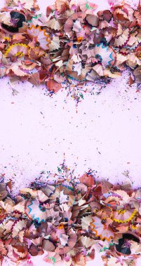 Ahşap talaşlar ve yumuşak pembe kağıt arka planında bileyiciden gelen renkli grafit kırıntıları. Üst Manzara. Poster, pankart ve kartlar için metin için boş alanı olan simetrik tasarım.