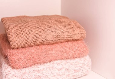 Bir gardırop rafında sıcak sonbahar ve kış örgü süveter yığını. Yaşayan mercanların gölgelerinde modern moda giysiler.