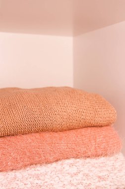 Bir gardırop rafında sıcak sonbahar ve kış örgü süveter yığını. Yaşayan mercanların gölgelerinde modern moda giysiler.