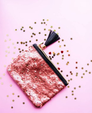 Bright composition of fashion accessories. Glitter sequins purse and decorative tinsel. Different objects on soft pastel background. Flat lay, top view.