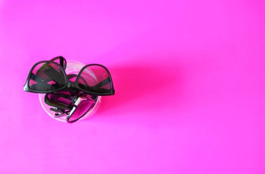 Sunglasses on pink pastel background. Glasses with black frames. Eye UV protection fashion accessories.