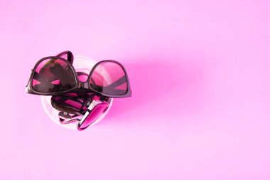 Sunglasses on pink pastel background. Glasses with black frames. Eye UV protection fashion accessories.
