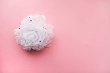 Yumuşak pembe arka planda beyaz kurdele. Şenlikli dekoratif öğe.