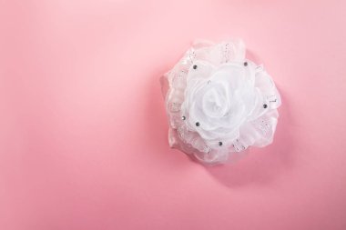 Yumuşak pembe arka planda beyaz kurdele. Şenlikli dekoratif öğe.