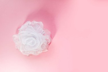 Yumuşak pembe arka planda beyaz kurdele. Şenlikli dekoratif öğe.