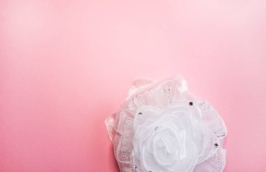 Yumuşak pembe arka planda beyaz kurdele. Şenlikli dekoratif öğe.