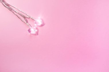 Yumuşak pembe arka planda iki küçük cam kalp. Sevgililer Günü sembolü. Dekoratif öge