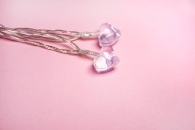 Yumuşak pembe arka planda iki küçük cam şeffaf kalp. Sevgililer Günü sembolü. Dekoratif unsur. Sevgililer Günü Kartı.