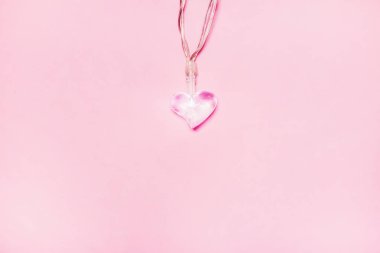 Yumuşak pembe arka planda iki küçük cam kalp. Sevgililer Günü sembolü. Dekoratif unsur. Sevgililer Günü Kartı.