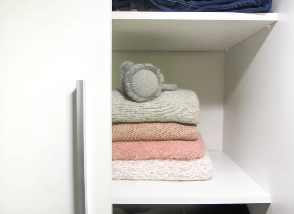 家居柜的白色架子上摆放着五颜六色的毛衣 套头衫和温暖的耳机 小空间组织 最低纲领概念 — 图库照片