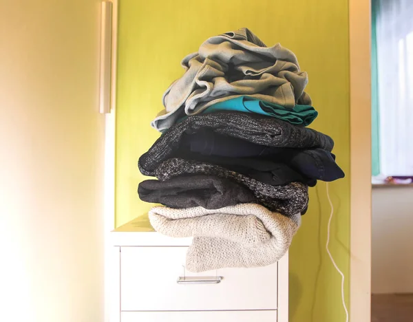 Home wardrobe with different clothes in disorder. Small space organization.