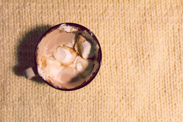 Bebida caliente de cacao fresco en una taza de cerámica con malvaviscos dulces derretidos sobre un acogedor fondo de punto —  Fotos de Stock