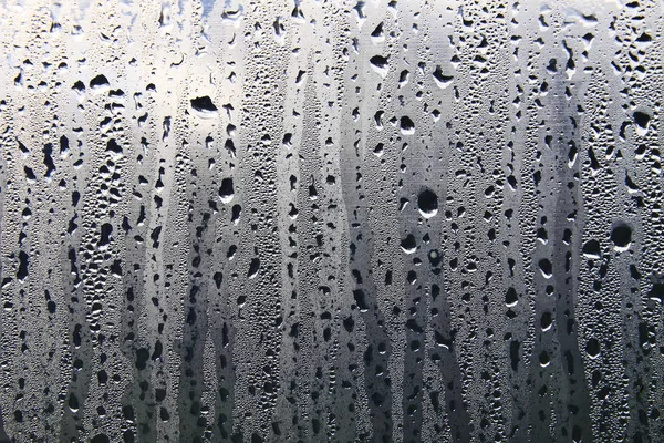 Islak şeffaf yüzeyde yağmur damlaları var. Sulu cam..