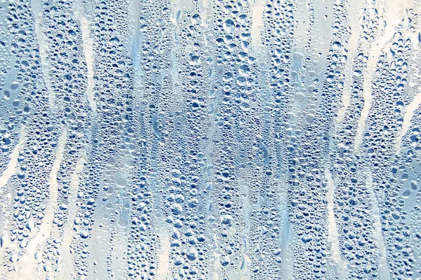 Islak şeffaf yüzeyde yağmur damlaları var. Sulu cam..